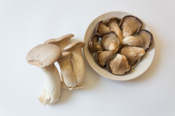 Shallow dish of Pleurotus ostreatus Oyster Mushrooms and Pleurotus eryngii King Trumpet Mushrooms, isolated on white, centered, food ingredient, horizontal aspect