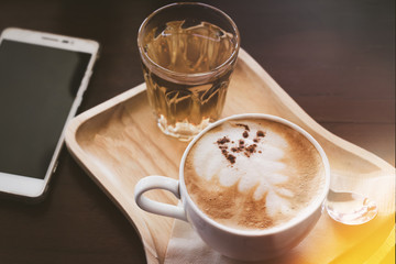 a cup of aroma  coffee  in the morning with mobile phone on the wood table.
