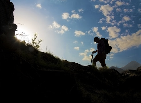Silhouette of a man hiking in mountains with backpack. 