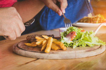 people's eating  delicious steak  on the brown wood table with fun and happy.