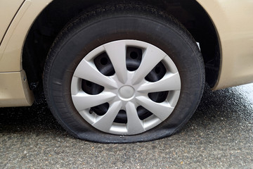 Uh-oh. Close up of car's flat tire in the rain.