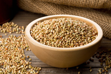 Raw, natural, uncooked buckwheat seed kernels in wooden bowl