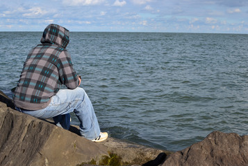 man thinking on a rock staring out into ocean