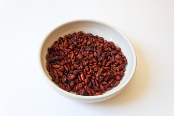 Centered view of white bowl of Capsicum annuum Pequin pepper dried red piquin bird peppers, food ingredient, isolated on white, horizontal aspect
