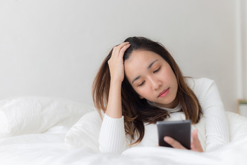 Happy women playing smartphone and smile on bed after wake up in the morning
