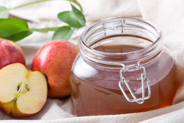 Closeup of glass jar apple juice with fresh apples on table