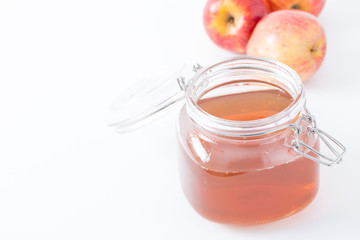 Glass jar of apple juice with fresh apple on white background