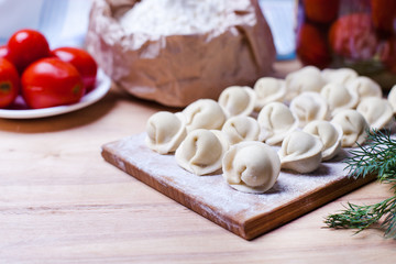 dumplings with meat on a wooden stand - cooking, raw unpeeled dumplings, national Russian, Ukrainian cuisine
