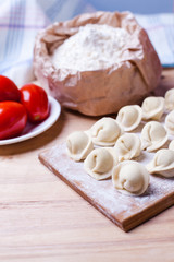 Fototapeta na wymiar dumplings with meat on a wooden stand - cooking, raw unpeeled dumplings, national Russian, Ukrainian cuisine