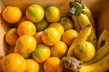 Banana and orange in wooden box.