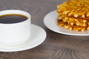 coffee cup with stack of belgian round waffles on wooden table