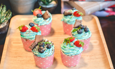 Cupcake strawbery with cream and chocolate  stick on the wood dish, grain, Blueberry, Selective focus