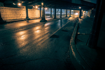 Dark city alley industrial train bridge underpass at night.