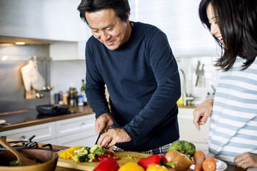 Asian couple cooking in the kitchen - obrazy, fototapety, plakaty