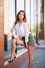 Young fashion woman in white shirt and short skirt at the mall window