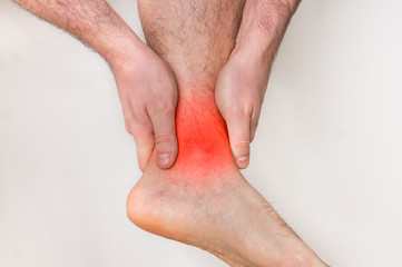 Man with ankle pain holding his aching leg