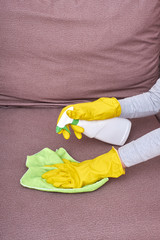 A picture of hands in yellow gloves cleaning the sofa