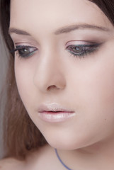 Girl with professional makeup and clean skin is looking down close-up