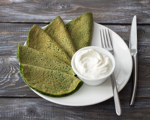 Spinach pancakes on a white plate on a wooden table, selective focus. Delicious healthy breakfast © olepeshkina