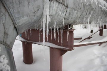 Elevated section of the pipelines with icicles hanging from the pipes in winter.