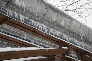 Elevated section of the pipelines with icicles hanging from the pipes in winter.