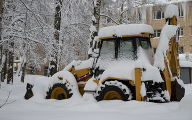 Snow clearing. Tractor clears the way after heavy snowfall.yellow excavator in winter in the snow