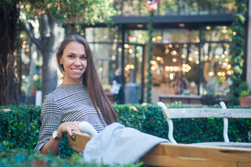 Smiling happy woman sitting on the bench in the city