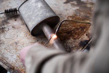 A man welds a metal with a gas burner