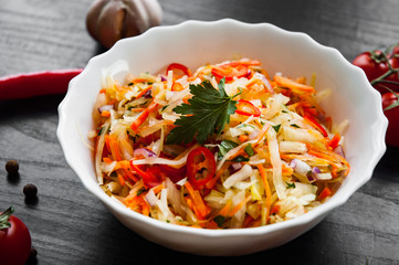 fresh vegetables salad with cabbage and carrot in bowl on a dark wooden background