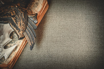 A hilt of a sword lies on the book on textile background copy space