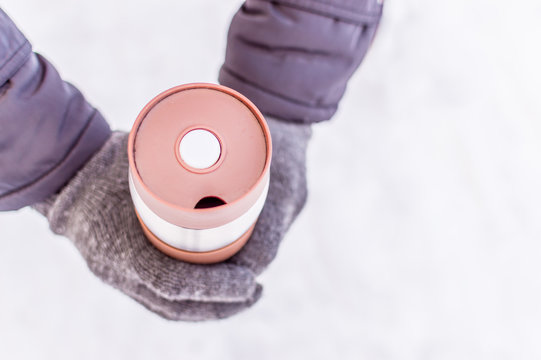 thermos in the hands of a man close-up against the snow