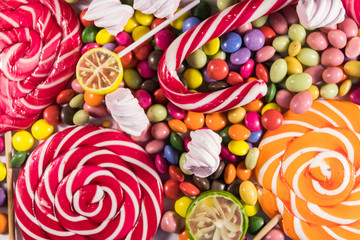 Background of colorful chocolate candies, lollipops, candy cane and marshmallows