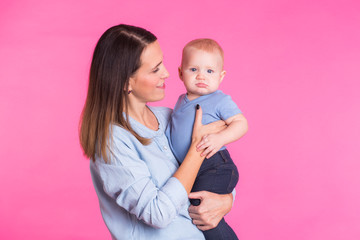 happy young mother with a baby child on pink background