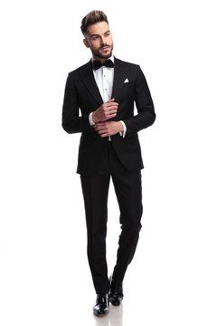 young sexy man in tuxedo and bowtie fixing his sleeve