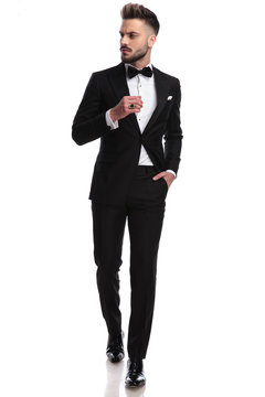 man in tuxedo wearing ring, walks and looks to side