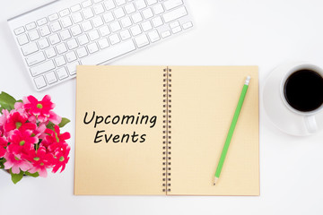 Concept Upcoming Events message on notebook with keyboard, pencil and coffee cup on white background.