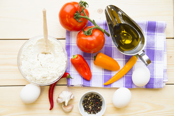 Cooking concept - red and yellow pappers, eggs, olive oil, cottage cheese and tomatos on wooden table. Set of healthy food products are sources of vitamins and minerals. Closeup, top view