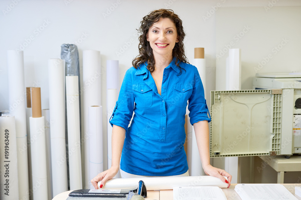 Poster portrait of smiling operational manager looking at camera posing in printing shop or publishing comp
