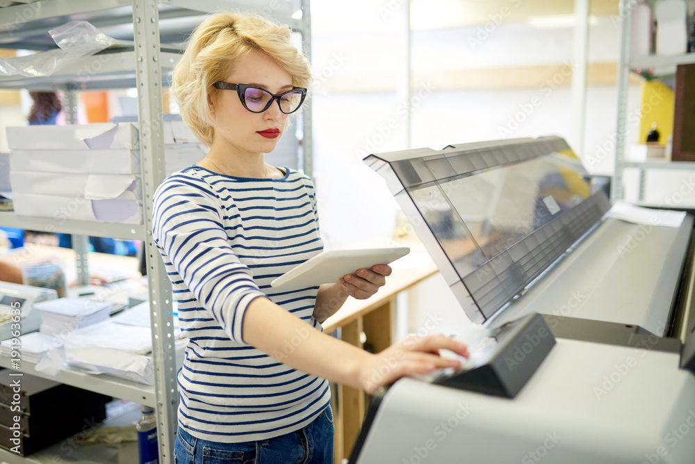 Aufkleber portrait of modern blonde woman using plotter machine operating it via digital tablet while working 