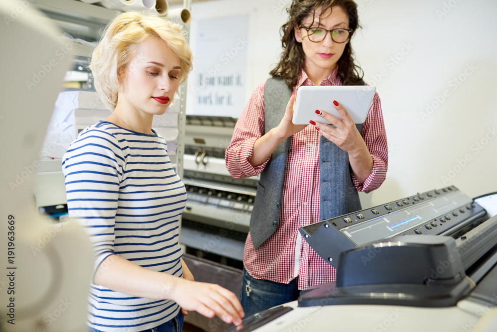 Aufkleber portrait of two women using plotter machine operating it via digital tablet while working in modern 