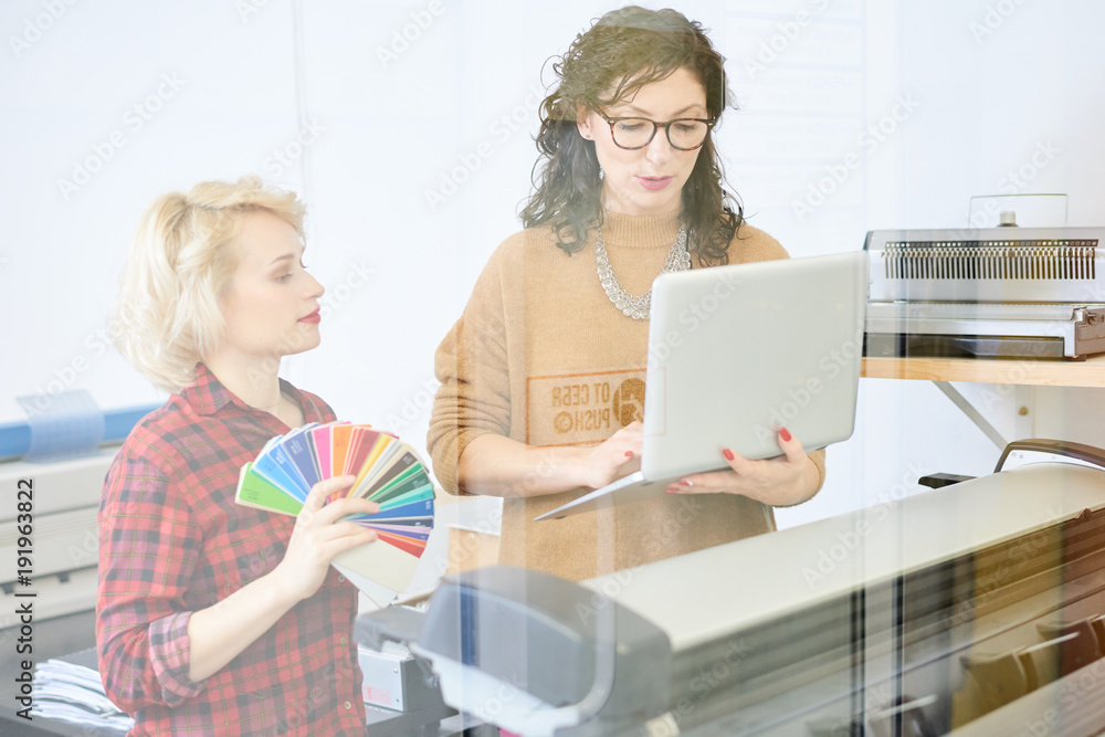 Poster portrait of two graphic designers using plotter machine operating it via laptop in modern printing s