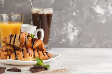 Fresh breakfast croissants with chocolate syrup, orange juice and cocoa with marshmelow. Copy...
