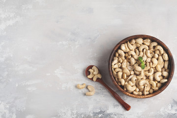 Cashew nuts in a wooden bowl, top view, copy space, food background. Healthy vegetarian food concept.