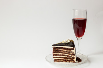 piece of chocolate cake on a glass saucer glass of red wine