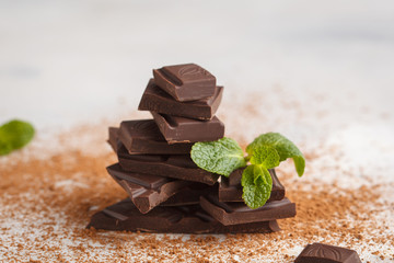 Stack of dark chocolate with mint leaf. White background, copy space. Macro