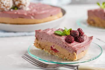 Piece of pink raspberry raw vegan cheesecake with coconut sweet raw balls. Healthy vegan food concept.