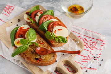 Caprese sandwich with mozzarella, tomato and basil on a wooden board. Italian cuisine concept.