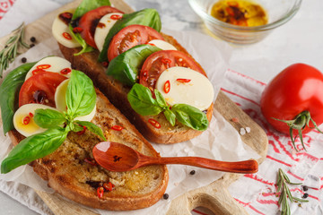 Caprese sandwich with mozzarella, tomato and basil on a wooden board. Italian cuisine concept.
