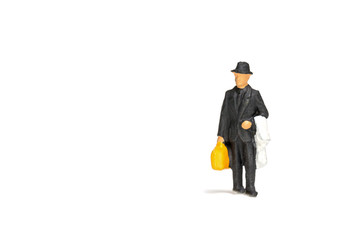 Miniature people ; Traveler holding a handbag standing on white background , Travel concept
