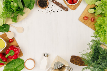 Frame of fresh green salad, red paprika, cherry tomato, pepper, oil and kitchenware on soft white...